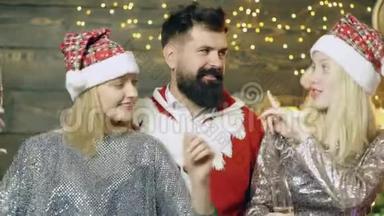 两个女孩和留胡子的男人的肖像，他们喝着香槟跳舞，迎接新年。 新年派对。 新年`